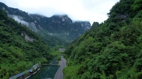 Aerial view of a winding road through a lush green mountain valley landscape 動画素材 342324716