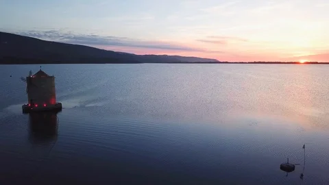 Aerial View A windmill on a sea lagoon at sunset Stock Footage 107847856