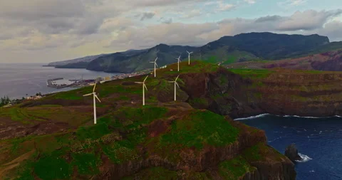 Aerial view of windmills standing on a cliff above the ocean in a picturesque Stock Footage 345809963
