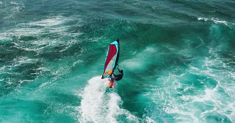 Aerial view of windsurfer gliding across blue ocean Stock Footage 63533133