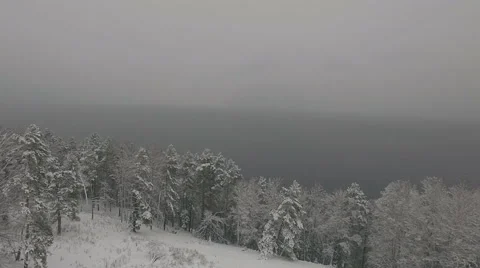 Aerial view from the winter forest to the large lake in the mist 4K Stock Footage 57251750
