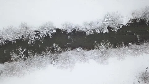Aerial view of winter mountain river surrounded by trees and banks of snow Stock Footage 85136392