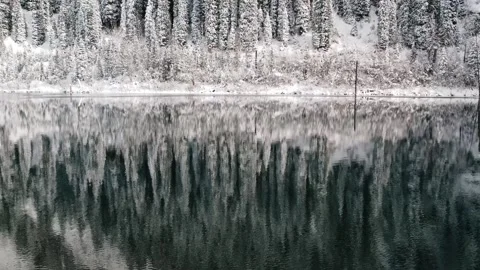 Aerial view of winter reflections on a calm alpine lake Stock Footage 321669600