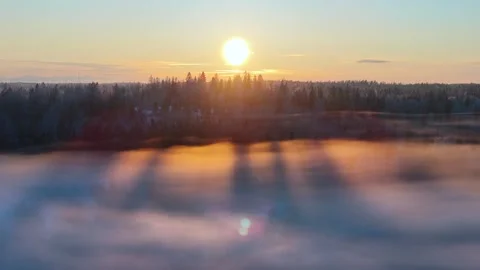 Aerial view to the winter sun setting behind the forest in Finland Stock Footage 257716664