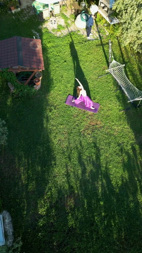 Aerial view of woman practicing warrior yoga pose in garden Video stock 345125553