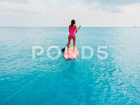 Aerial view of woman on stand up paddle board in blue ocean. Stock Photos