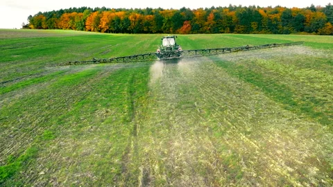 Aerial view The work of a tractor spraying pesticides and fertilizer on a large Stock Footage 234282393