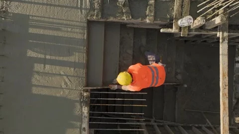 Aerial View: A worker skillfully smooths out wet concrete on a stair landing Stock Footage 296075229