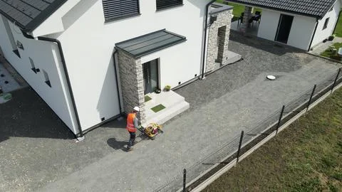 Aerial view of a worker working with a vibrating plate machine in front of house Stock Photos