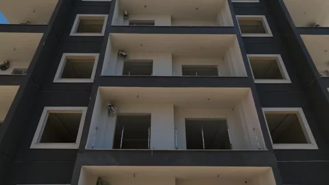 Aerial View: Workers scale scaffolding to install a modern facade on a high-rise Stock Footage 296127965