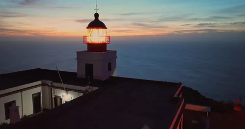 Aerial view to working lighthouse at dusk time located on a picturesque rock Video stock 270957227