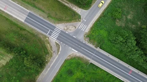 Aerial View of a Yellow Car at Intersection Surrounded by Greenery During Stock Footage 280887291