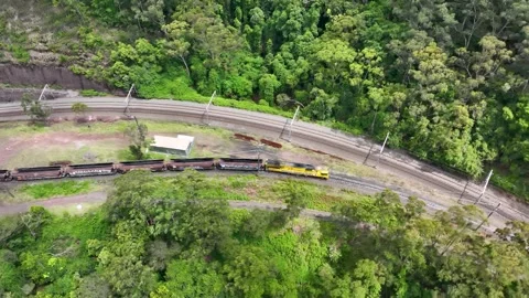 Aerial view of yellow freight train locomotive traveling through lush green.. Stock Footage 337783233