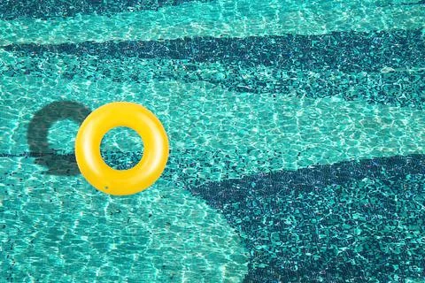 Aerial view of yellow ring float in a  blue swimming pool under bright sunny Stock Photos