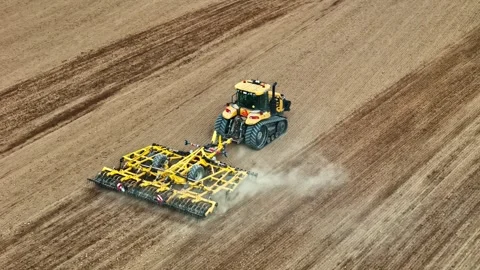 Aerial View of Yellow Tracked Tractor Cultivating Dry Open Field Stock Footage 331764446