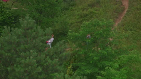 Aerial view of young active couple hiking together on green hills taking their Video stock 164726576