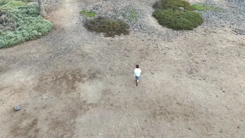 Aerial view of young boy running across rocky terrain Stock Footage 328091004