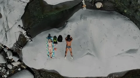 Aerial view of young couple sunbathing on white riverside gravel bar Stock Footage 346179908
