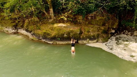 Aerial view of young guy jumping in mountain forest lake. Taken by drone Stock Footage 118353845