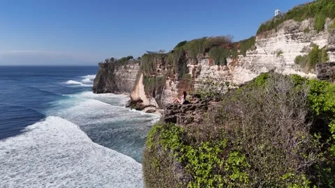 Aerial view of young lady is seating on a cliff Uluwatu, in in Bali, Indonesia Stock Footage 315752049
