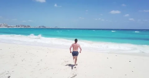 Aerial view of a young man jumping into the Caribbean Sea, Cancun, Mexico Stock Footage 168027923