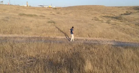 Aerial view of young man walking and enjoying with open arms, on the outskirt Stock Footage 133572302