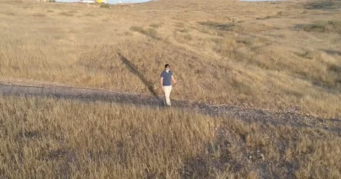 Aerial view of young man walking and enjoying with open arms, on the outskirt Stock Footage 133746372