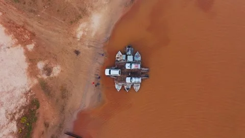 Aerial views showcase a rustic ferry transporting vehicles and people across a 스톡 동영상 308406122