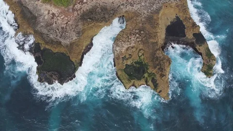 Aerial: waves crash into cliffs spraying salt in Nusa Lembongan 4K Drone Clip Stock Footage 103816554