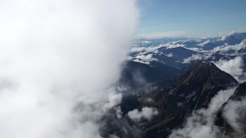 Aerial of white clouds over rocky mountain ranges during winter Stock Footage 77814072