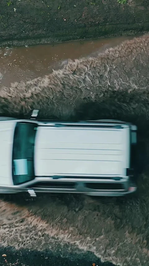 Aerial of a white SUV driving through muddy water on rugged terrain... Vídeo Stock 344332631