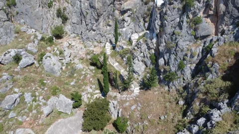 Aerial wide angle of chapel emerging from cave on rocky mountain slope Stock Footage 343932638