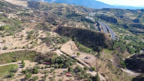Aerial wide angle orbit view of highway overpass amidst wild terrain Stock Footage 343961497