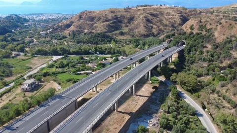 Aerial wide angle view of highway bridge over plain entering tunnel Stock Footage 343962806