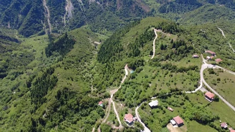 Aerial wide angle view of mountain village and winding forest road Stock Footage 343946679