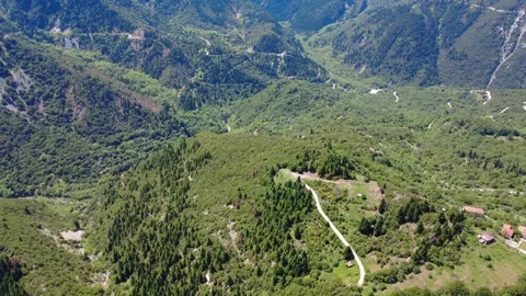 Aerial wide angle view of mountain village and steep forest road Stock Footage 343948087