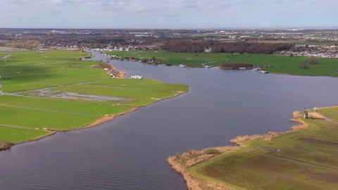 Aerial wide angle view over a wide river winding through vibrant green Stock Footage 339224923