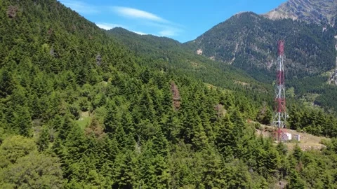 Aerial wide angle view of telecom tower beside dense mountain forest Stock Footage 343947313