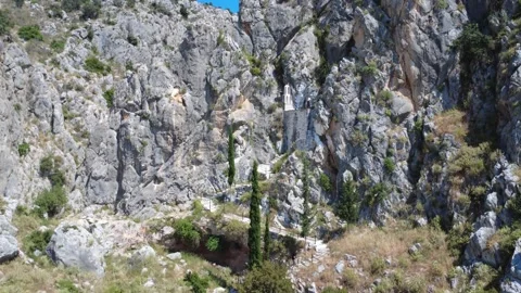 Aerial wide angle view of white chapel hidden among cliffs at canyon entrance Stock Footage 343932608