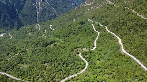 Aerial wide angle view of winding mountain road through green canyon Stock Footage 343945516