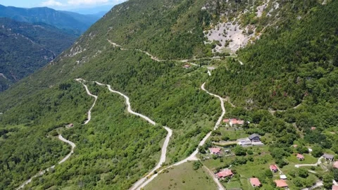 Aerial wide angle view of winding mountain road and valley village Stock Footage 343947883