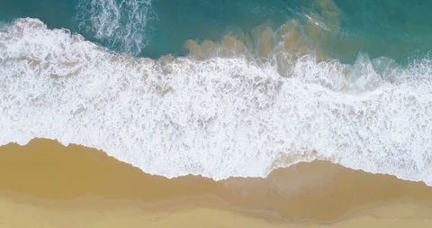 Aerial wide shot of waves breaking on pristine golden sandy beach high altitu Stock Footage 87572091