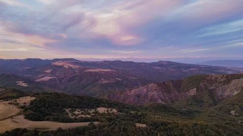 Aerial wide view of dramatic pink and purple sunset sky over rolling mounta.. Stock Photos