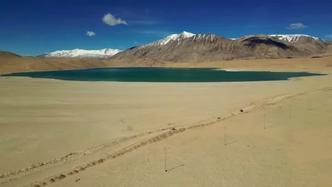 Aerial wide view of vehicles cutting through barren landscapes near the lake. Stock Footage 310807002