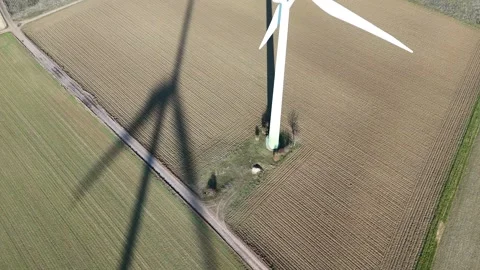 Aerial Wind Turbine Casting Shadow Across Agricultural Fields Vídeos de archivo 327974387