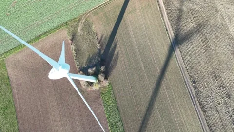 Aerial Wind Turbine Casting Shadow Across Agricultural Fields Vídeos de archivo 327974745