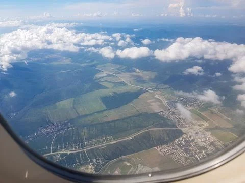 Aerial window view of fields and mountains with clouds airplane travel hori.. Stock Photos