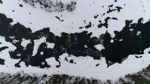 Aerial winter dark river scene with snow, ice and water flowing. Filming above Stock Footage 78736879