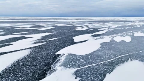 Aerial winter flyover over patterned sea ice moving toward an ice fishing area Stock Footage 332045921