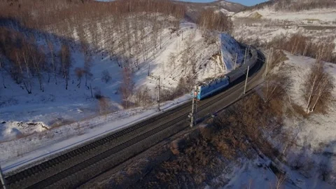 Aerial winter modern passenger train moving through snow rural landscape railway Stock Footage 317963725